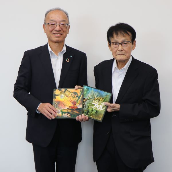絵本を持った毎日興行株式会社代表取締役社長と教育長